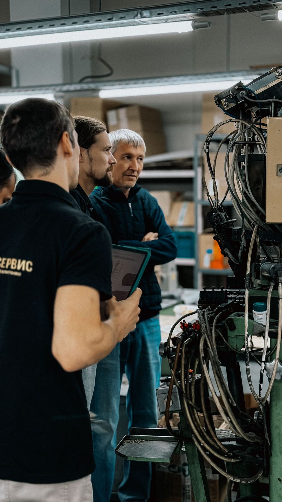 Engineers with a tablet discussing a machine on the production line.