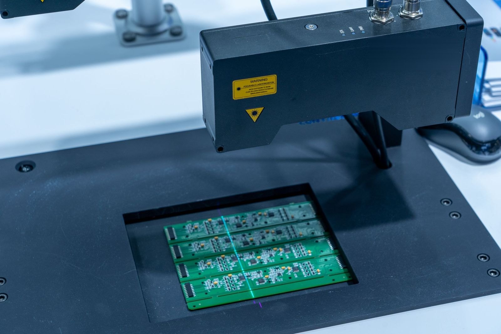 Laser inspection head scanning circuit boards in an automated station.
