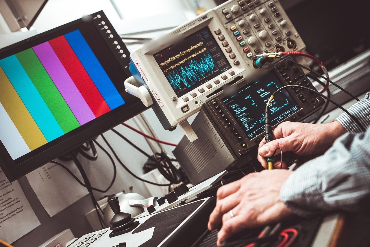 Digital oscilloscope showing live waveforms on a test bench, an engineer probing a signal.
